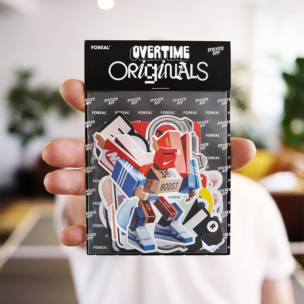 Hand holding a pack of "Overtime Originals" stickers featuring colorful, dynamic designs. Background blurred, focus on stickers.