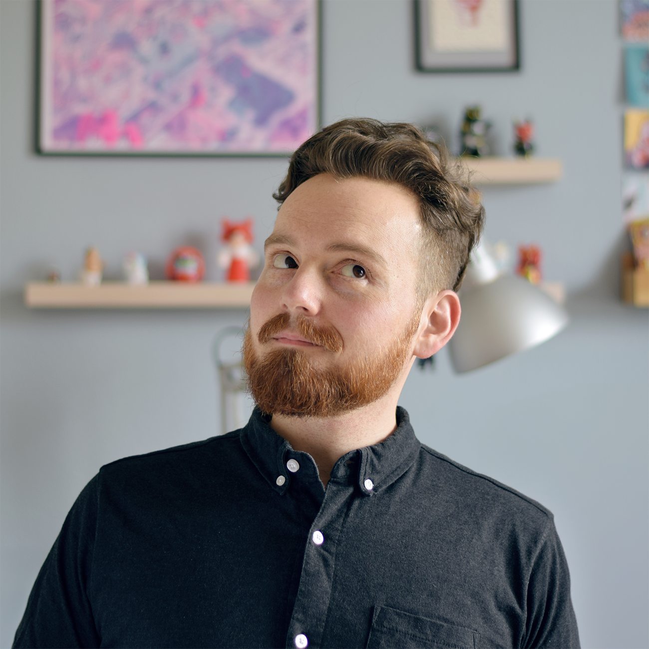 profile picture or daniel harisberger standing in a black shirt in front of paintings and art