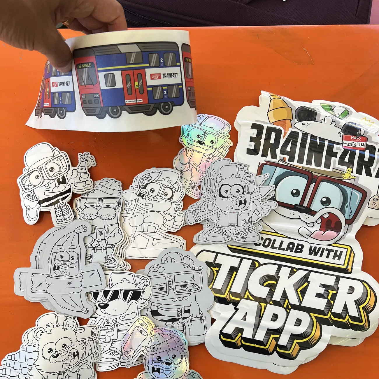白黒のダイカットステッカーの上に掲げた、「In every fart is art」の看板付きBrainfart x StickerAppのS8 World電車ラベル