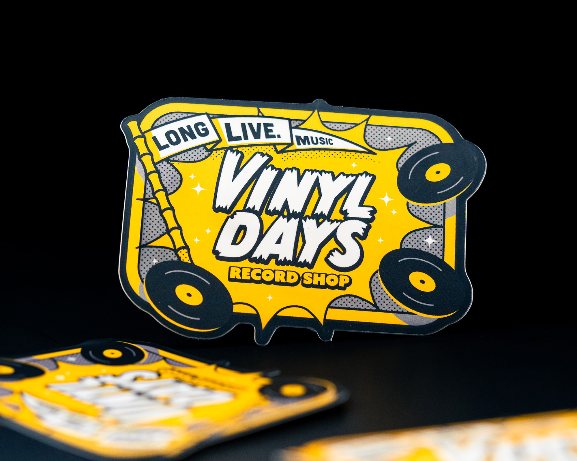 Sticker with "Vinyl Days Record Shop" text, surrounded by vinyl records on a yellow background. Subtext reads "Long Live Music."