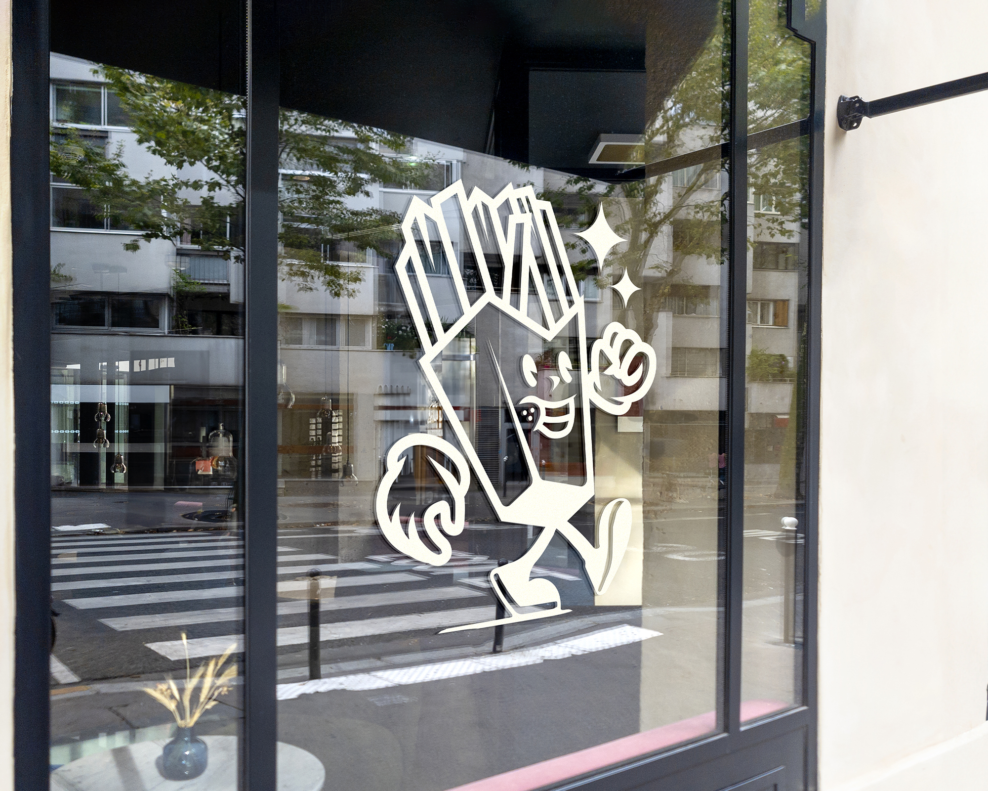 Cartoon French fry character, on transfer vinyl, on a window, smiling and running with one arm raised. Building and tree reflections in the glass.
