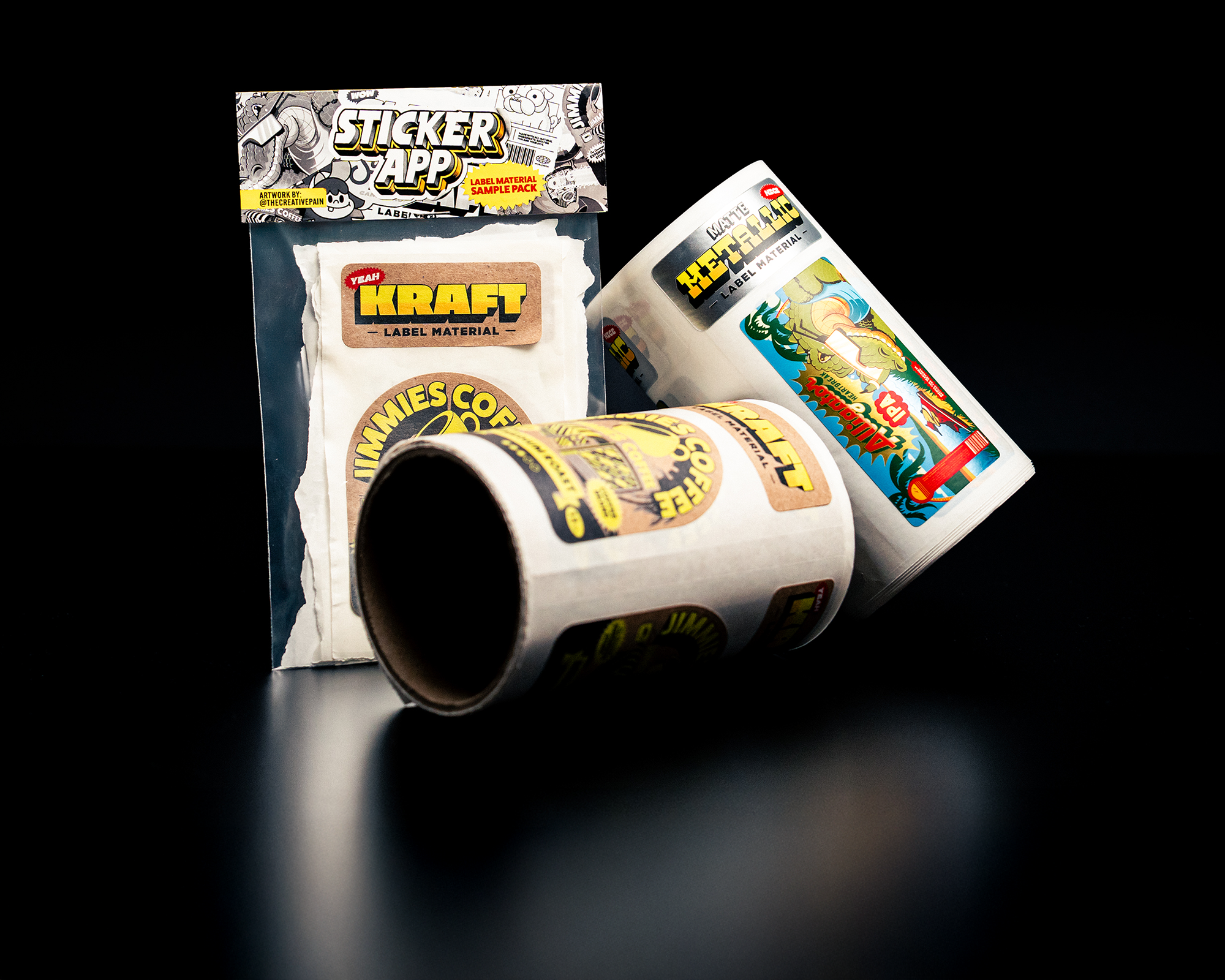 Rolls of custom labels featuring various designs and a package labeled "Sticker App" on a black background.